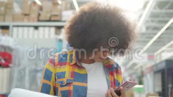 肖像非洲妇女留着非洲发型手里拿着手机在部门的商店都要修理视频的预览图