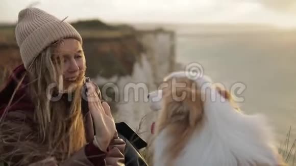 年轻女子的肖像给狗五只握住她的爪子诺曼底悬崖上的好友视频的预览图
