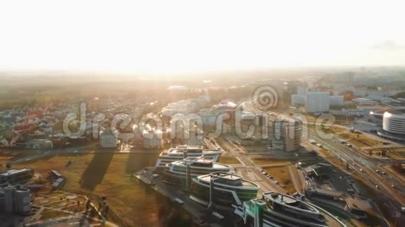 在晴朗的秋日日出期间在白俄罗斯明斯克的现代城市建筑和公园全景上空飞行的无人机视频的预览图