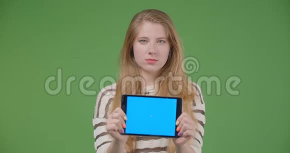 用平板电脑拍摄年轻漂亮的白种人女性的特写镜头并显示蓝色的色度键屏幕来拍摄它视频的预览图