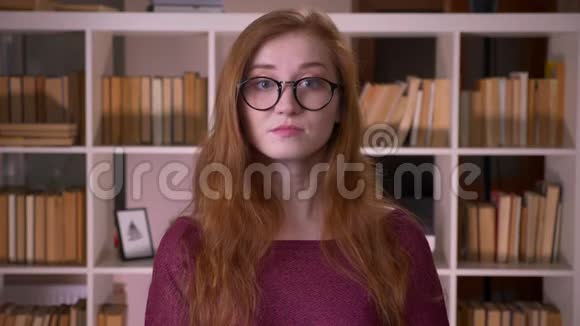 年轻的红头发迷人的白种人女学生戴着眼镜点头说是看着镜头视频的预览图
