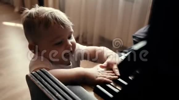 小可爱的小男孩脸上带着微笑慢动作地敲着钢琴键视频的预览图