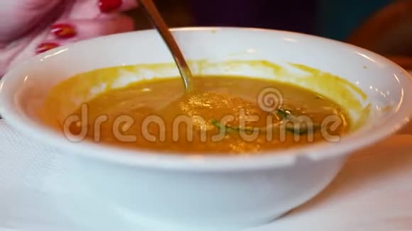汤的特写女人在咖啡馆里吃白色盘子的汤匙视频的预览图