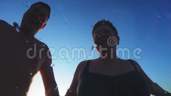 成年夫妇在日落时跳进水里一对男女跳进水里在水下游泳视频的预览图