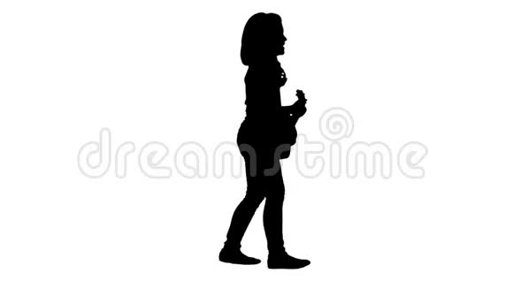 剪影可爱的小女孩走路和唱歌同时在四弦琴上演奏视频的预览图