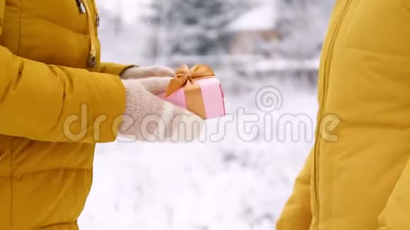 女性手拿着一个惊喜礼盒在冬季景观的背景上有一个金色的蝴蝶结礼物和快乐视频的预览图