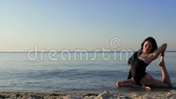穿着黑色紧身衣的健身女性身体运动坐在海滩上的做瑜伽和伸展运动健身运动瑜伽视频的预览图