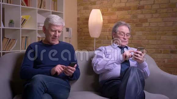 老年男性朋友静静坐在自己的智能手机中被吸引和忙碌的肖像视频的预览图