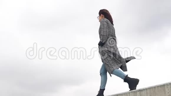 一位年轻女子走在水泥栅栏上穿外套的女孩视频的预览图