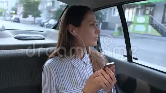 美丽的女人坐出租车听耳机音乐视频的预览图