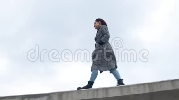 一位年轻女子走在水泥栅栏上穿外套的女孩视频的预览图