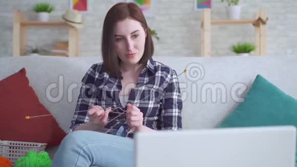 合上坐在笔记本电脑前沙发上学习编织的女人视频的预览图