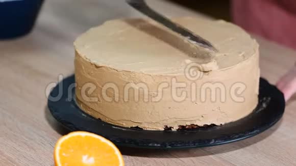 在巧克力海绵蛋糕上涂上奶油的特写家庭烘焙蛋糕在旋转的支架上装饰蛋糕视频的预览图