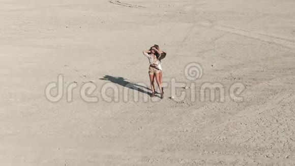 空中射击两名年轻女子站在沙漠中央他们举起手来捕捉阳光视频的预览图