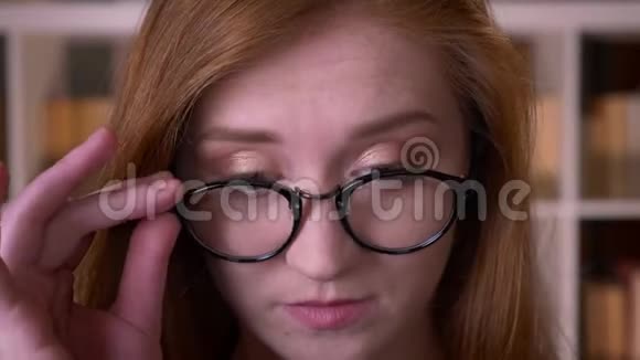 年轻的红头发迷人的白种人女学生戴着眼镜看着镜头开心地笑着视频的预览图