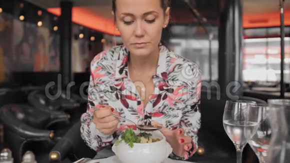 穿着五颜六色的衬衫勺子的漂亮女游客吃着传统的法式洋葱汤汤里有面包和青菜视频的预览图