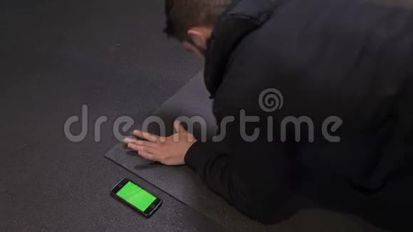 成年肌肉运动员用绿色屏幕的手机顶起特写镜头室内还有视频的预览图