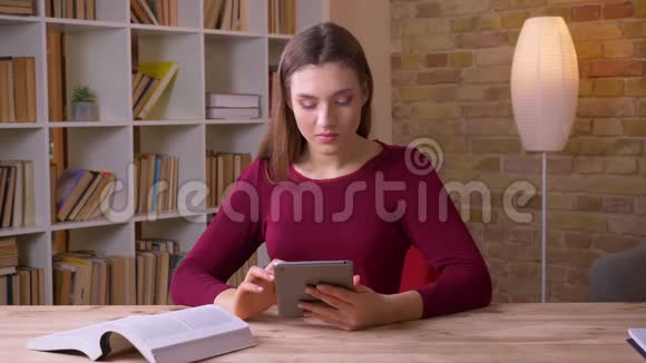 年轻的黑发女商人工作平板电脑和书籍在办公室视频的预览图