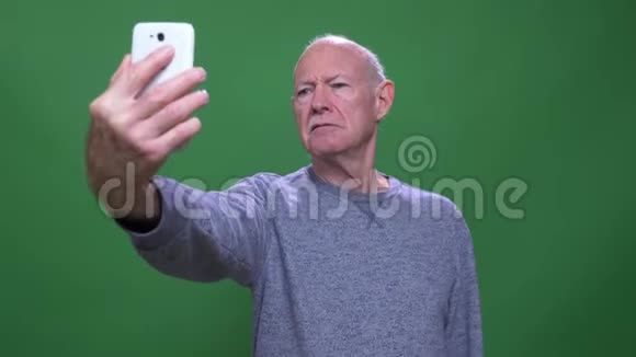 一个老白种人带着自拍在电话里看镜头的特写镜头背景与镜头隔绝视频的预览图