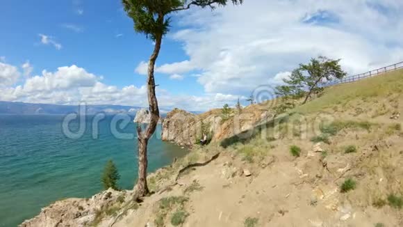 鸟瞰一个女孩坐在岩石海岸上画画美丽的风景视频的预览图