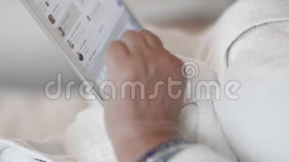 一位穿着白色特里长袍躺在床上的老妇人使用平板电脑在信使上写了一条信息动作缓慢接近视频的预览图