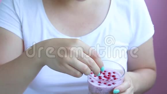 在公寓里美甲少女的双手装饰着一个玻璃上面有粉色背景的早餐水果视频的预览图