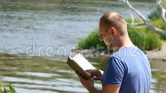 年轻的学生在河岸上读一本书有书的游客视频的预览图