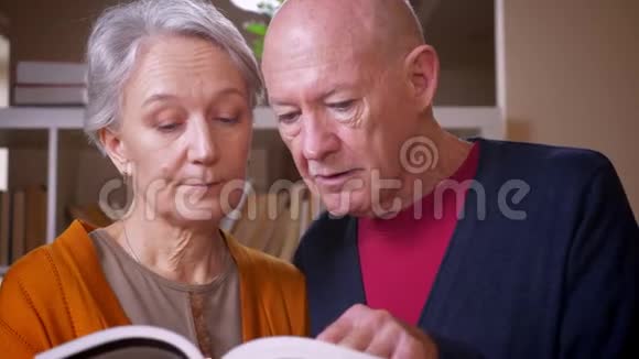 高白种人夫妇在电视上一起阅读书籍专心致志对图书馆感兴趣视频的预览图