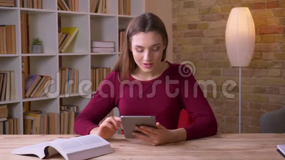 年轻漂亮的黑发女商人工作的平板电脑和书籍集中在办公室视频的预览图