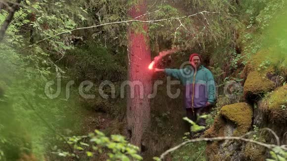 人类探险家站在绿色的树木中手持红色燃烧信号耀斑被某人发现库存数据视频的预览图