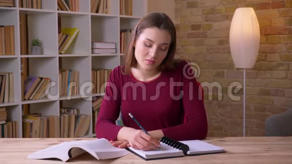 年轻的黑发女学生读书和做笔记在办公室视频的预览图