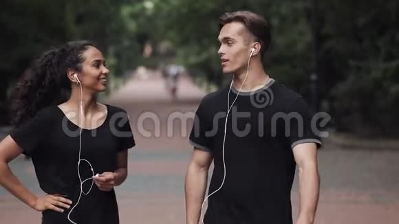 年轻的高加索男人和穆斯林女孩在公园里说笑摘下耳机看上去很快乐视频的预览图