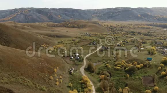 山脚下有一个舒适的小村庄有黄色的秋树和山坡视频的预览图