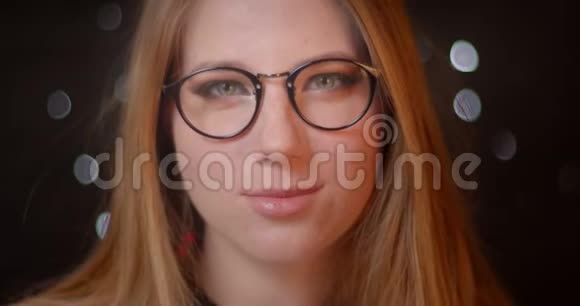 金发模特在眼镜上有明亮的妆容在bokeh背景下正对着相机微笑视频的预览图