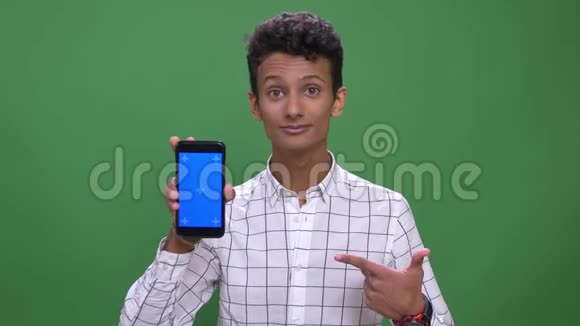 用手机拍摄年轻迷人的印度男性的特写镜头并将蓝色屏幕显示到背景隔离的相机上视频的预览图