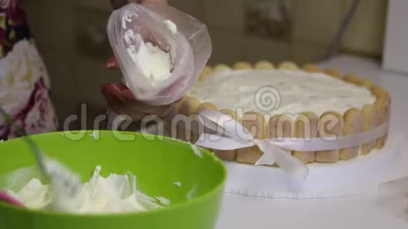 桌子上有一块萨沃亚迪饼干蛋糕用丝带绑着蝴蝶结女人把奶油放进糕点袋里视频的预览图