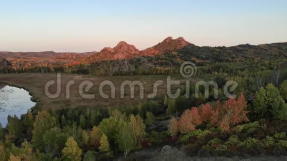 黄昏的秋景在红日落日的光线下岩石山和山的顶部视频的预览图