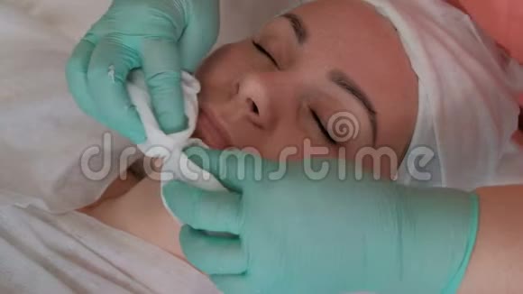 一个女孩闭着眼睛在美容院做一个恢复活力的手术手套里的美容师的手专业的美容师视频的预览图