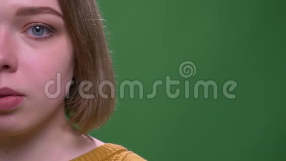 特写半脸拍摄年轻迷人的短毛女性看镜头背景隔离在绿色视频的预览图