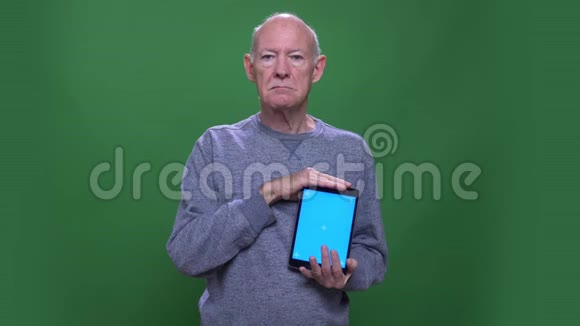 用平板电脑拍摄老白种人的特写镜头用蓝色屏幕观看背景摄像机视频的预览图