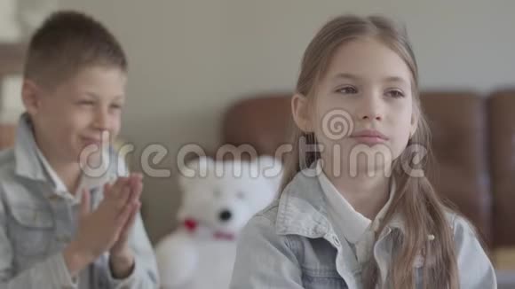 肖像可爱的孪生兄弟淘气的男孩在舒适的客厅里拉着他可爱的妹妹的头发微笑着视频的预览图