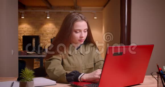 漂亮的十几岁女孩用笔记本电脑工作的肖像在办公室获得了成功视频的预览图