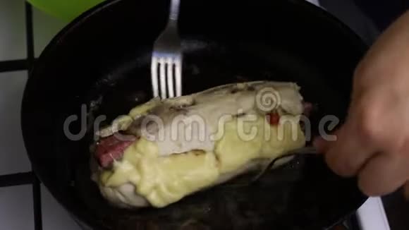 在一个加了黄油的加热煎锅里鸡角卷被炸了一个人用叉子翻卷你可以看到油是如何沸腾的视频的预览图
