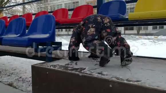 一个穿着冬季连衣裙的小孩子爬上了台阶俄罗斯的冬天体育论坛黄昏视频的预览图