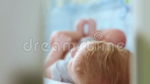 一个小蹒跚学步的孩子在婴儿床笑侧视通过一个小床改变焦点快乐的童年视频的预览图