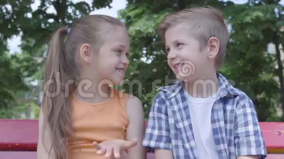 肖像可爱的男孩和女孩坐在秋千上在公园里跳舞在镜头里玩得很开心一对夫妇视频的预览图