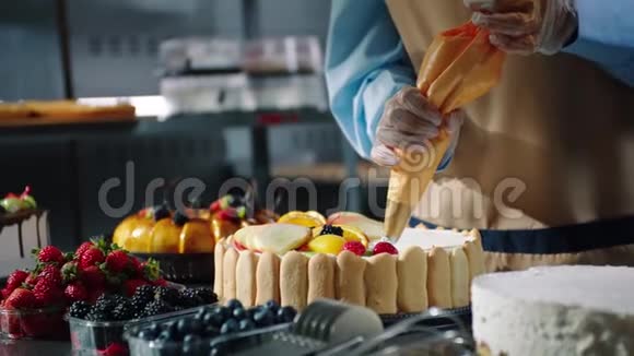 在近景的餐桌上糖果师为节日蛋糕添加了奶油视频的预览图