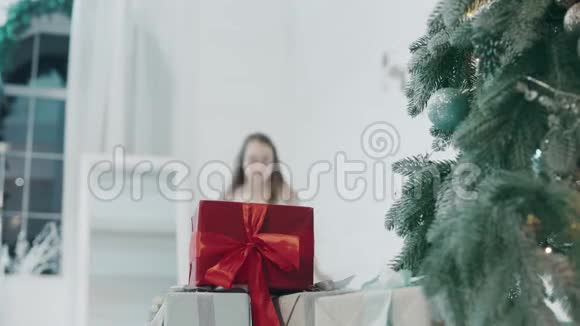漂亮的女孩在新年装饰的房间里看礼物视频的预览图