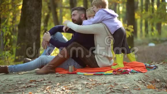 五彩缤纷的秋天家谱快乐微笑的年轻父母和小儿子躺在秋叶里年轻父母和视频的预览图