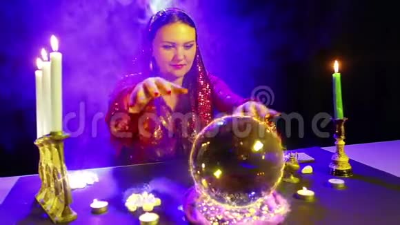 一个在魔术沙龙里的吉普赛人正在用水晶球表演魔术从水晶球中出现了一个炽热的美元符号视频的预览图